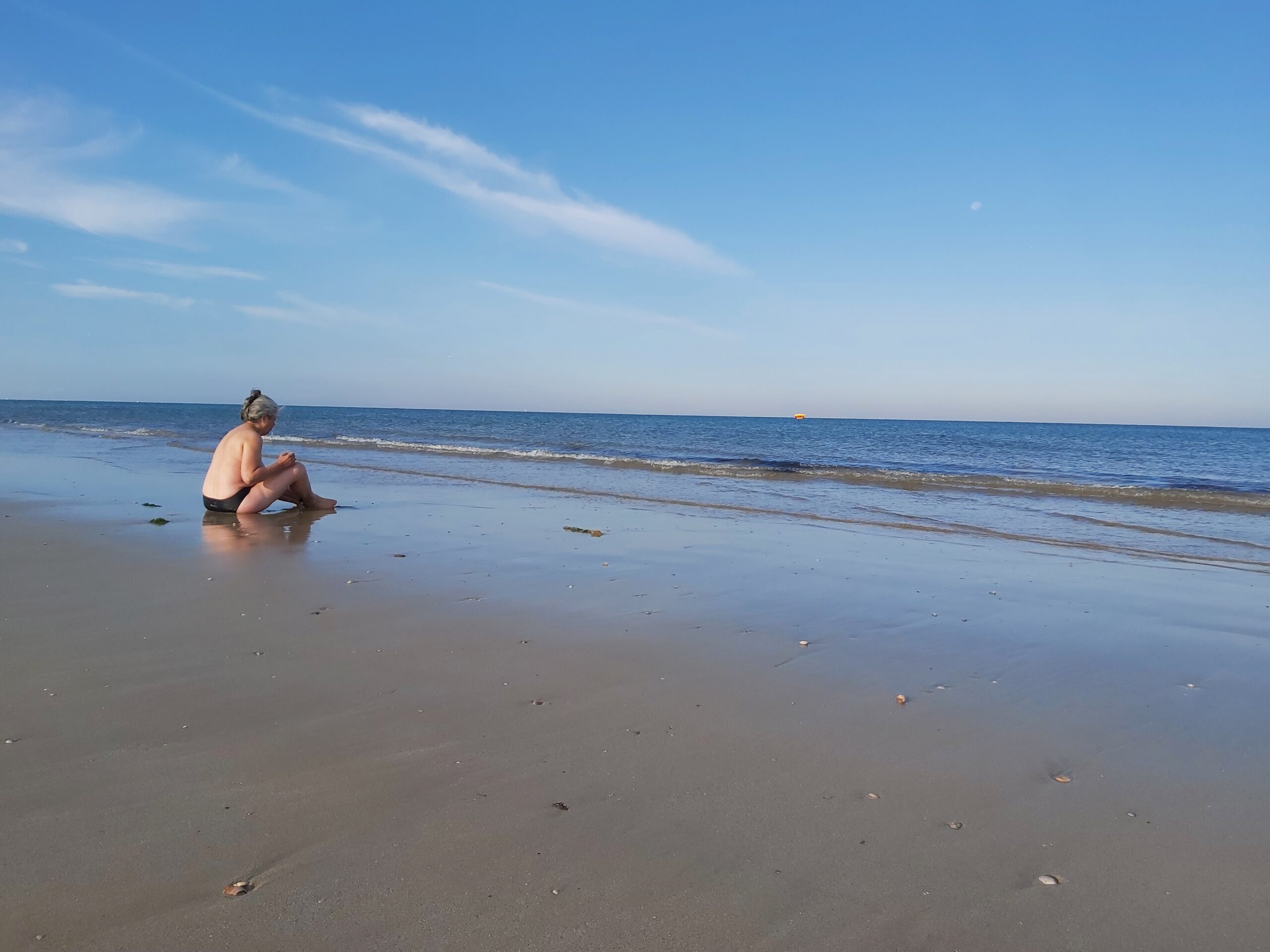 Une Femme est assise et se nettoie énergétiquement dans l'eau face à l'océan